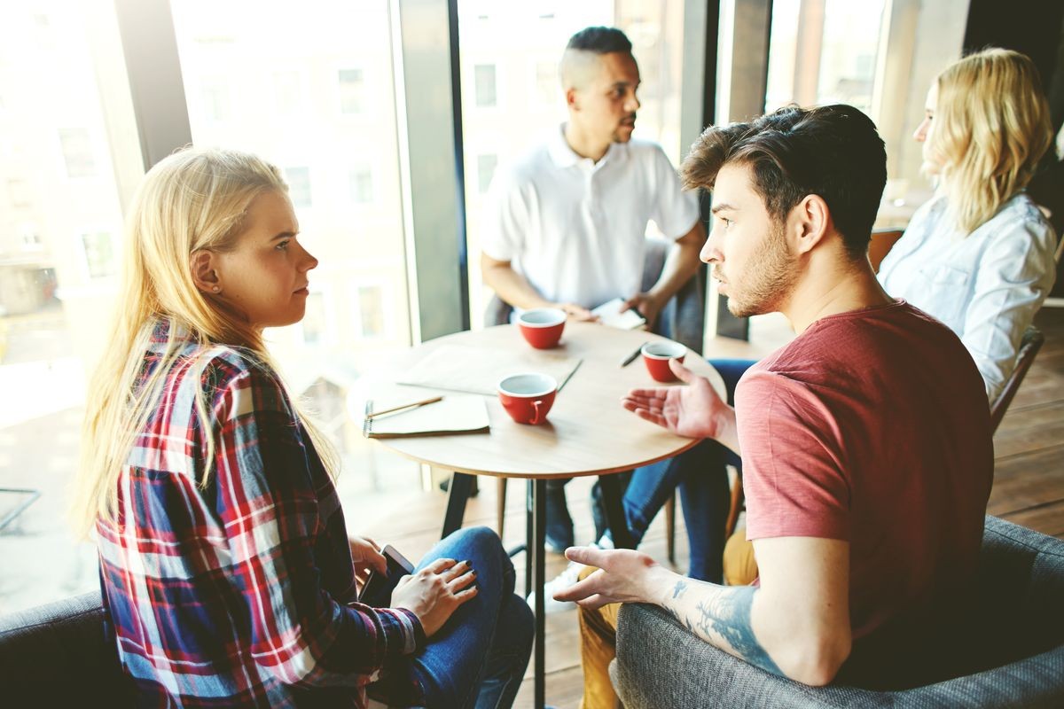 Four young friends or coworkers having coffee together in cafe, couples talking with each other
